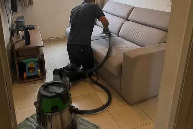 Profissional da Flex Clean higienizando um estofado claro em atendimento residencial