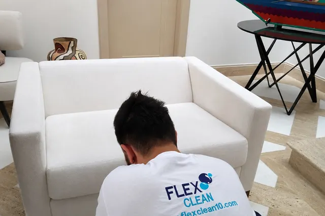 Profissional da Flex Clean higienizando uma poltrona branca na casa do cliente