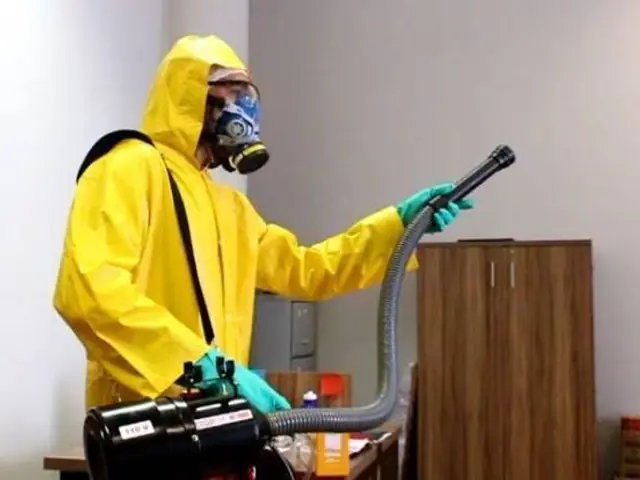 Técnico aplicando desinfecção e sanitização em ambiente interno